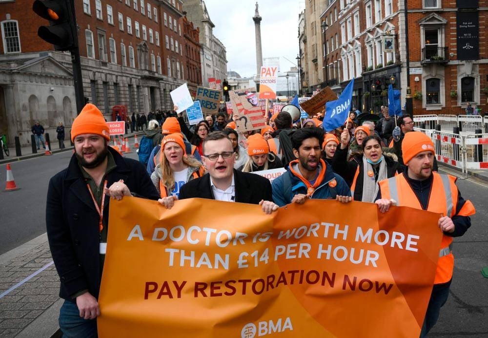 Demonstrators hold placards during a march by so-called ‘junior doctors’, physicians who are not senior specialists but who may have years of experience, through central London on April 11, 2023, in a dispute with the government over pay. - File pic by AFP