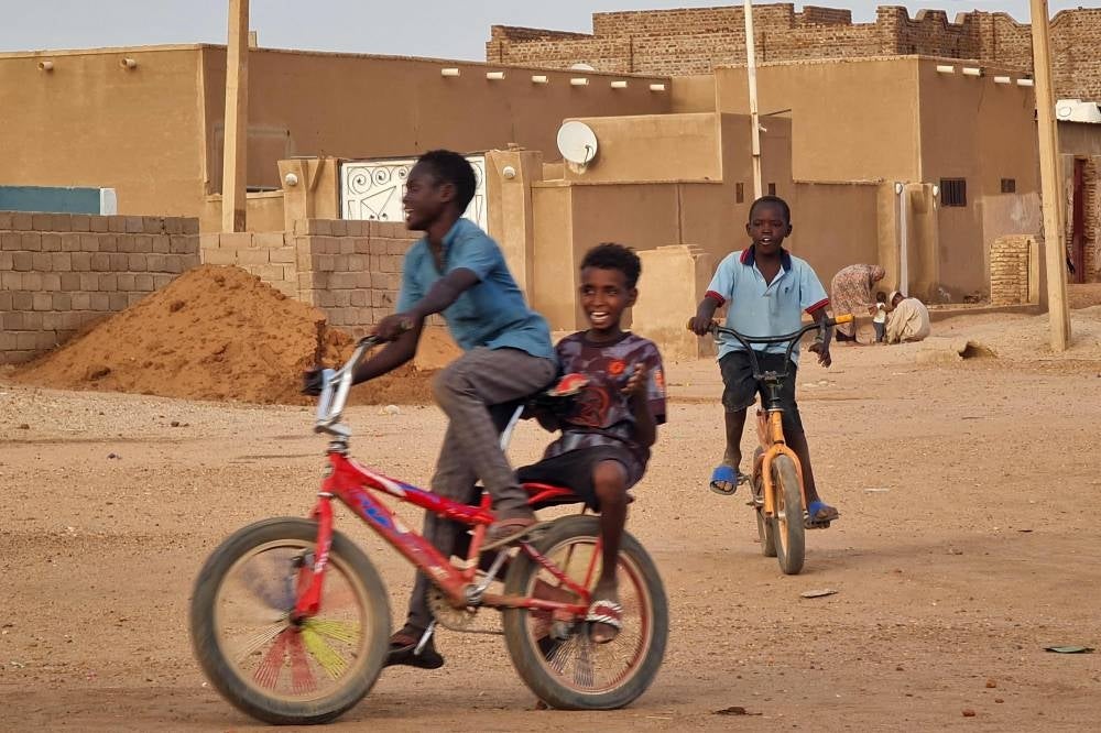 Children cycle along a street in Khartoum on June 14, 2023 - AFP