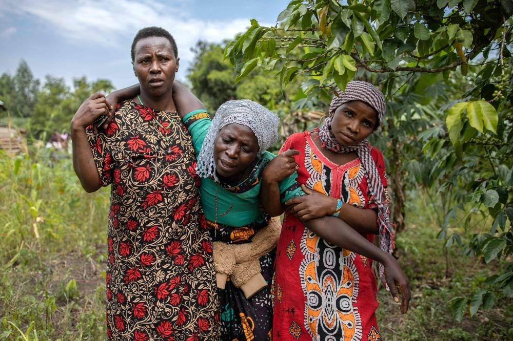 A mourning relative is conforted during the funeral of Florence Masika and Zakayo Masereka in Mpondwe on June 18, 2023. - Photo by AFP