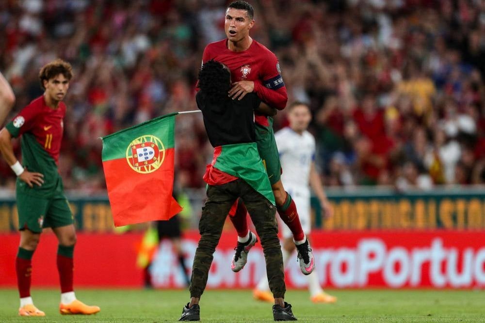 A supporter invades the pitch and grabs Portugal’s forward Cristiano Ronaldo during the UEFA Euro 2024 group J qualification football match between Portugal and Bosnia-Herzegovina at the Luz stadium in Lisbon on June 17, 2023 - Photo by AFP