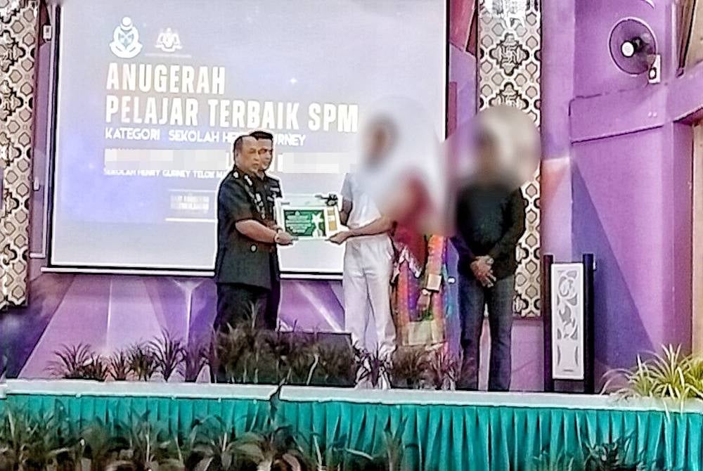 Ajidin (left) presenting an award certificate and cash to one of the excellent students at Henry Gurney School in Telok Mas on Monday.
