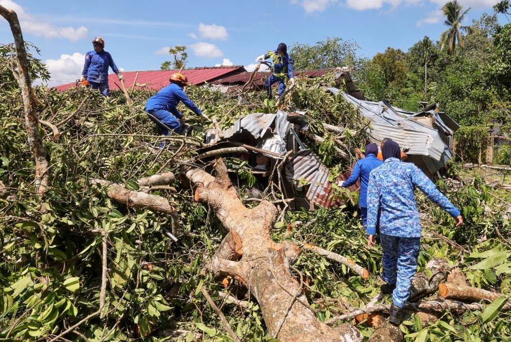 Pasir Puteh Malaysian Civil Defence Force personnel at a storm-hit house in Kampung Permatang Sungkai. - BERNAMA