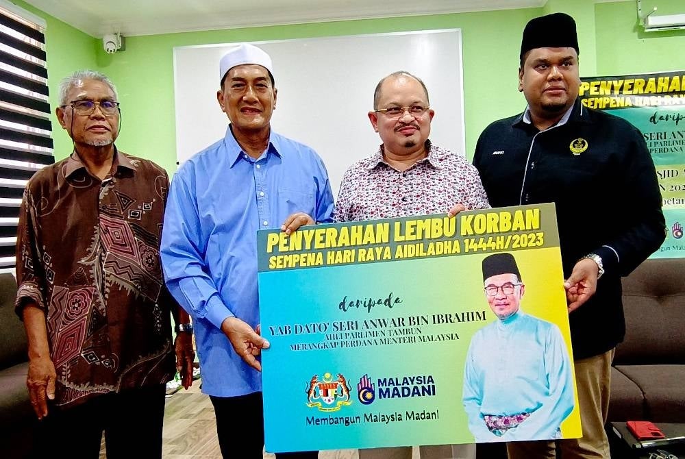 Shamsul Iskandar (second from right) presents a symbolic card of the handover of sacrificial cows to the Chairman of Al-Amaniyyah Mosque, Sukiman Jalil (second from left) at the Tambun Parliament's Sacrificial Cow Handover program in conjunction with Hari Raya Aidiladha - FILE PIX 