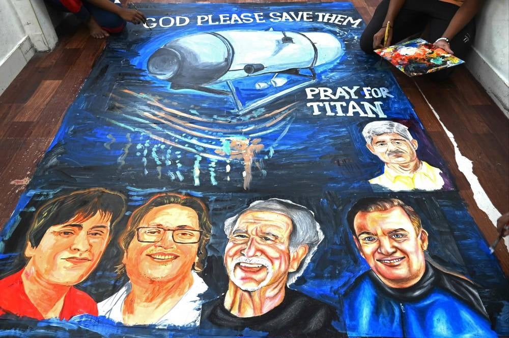 Art school students give final touches to a painting depicting five people aboard a submersible named Titan, that went missing near the wreck of the Titanic, in Mumbai on June 22, 2023. - Photo by AFP