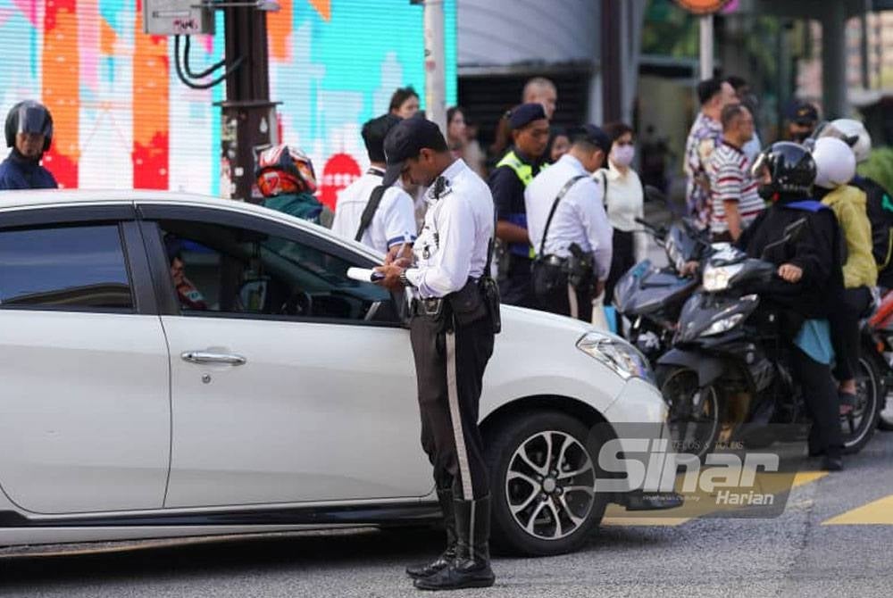 Policemen issued summons to traffic offenders during Kuala Lumpur Police Obey Traffic Rules Operation on Monday. - Photo: SINAR HARIAN/Rosli Talib.