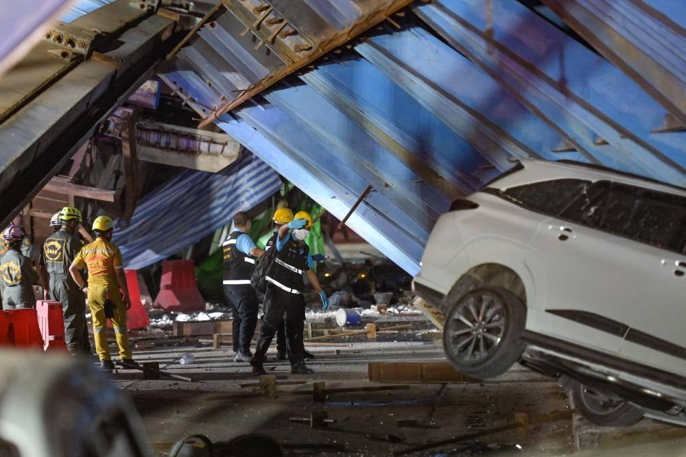 Forensic police and rescue workers inspect the scene after a construction girder on an elevated tollway collapsed, killing at least one person, in Lat Krabang district in Bangkok - AFP 