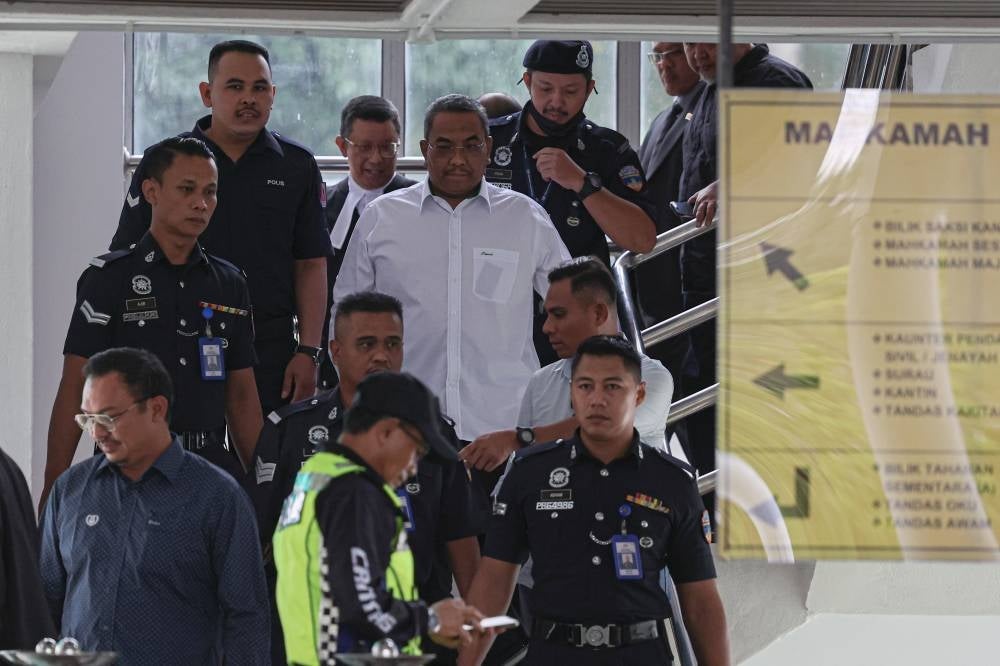 Sanusi (centre, dressed in white) escorted by the police out of the Selayang Court on Jan 18 after pleading not guilty to two charges of seditious remarks.