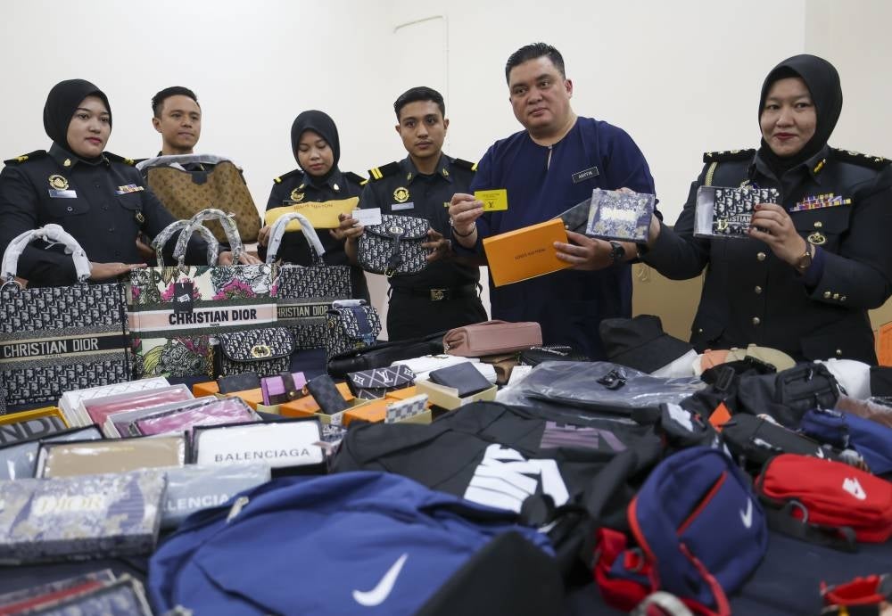 Kuala Lumpur Domestic Trade and Cost of Living Ministry director Ariffin Samsudin showing some of the fake foreign goods seized from nine premises at Petaling Street during its Ops PUTRA 3.0 on Tuesday. - Photo by Bernama