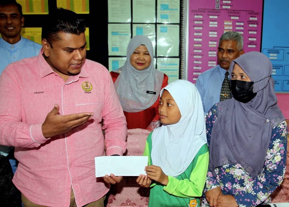 Hulu Kinta assemblyman Muhamad Arafat Varisai Mahamad (left) with Nur Alisha Adawiyah Mohd Yusri who was injured when a toilet cistern dislodged from its mounting and crashed onto her at Sekolah Kebangsaan Perpaduan at Taman Perpaduan. - Photo by Bernama