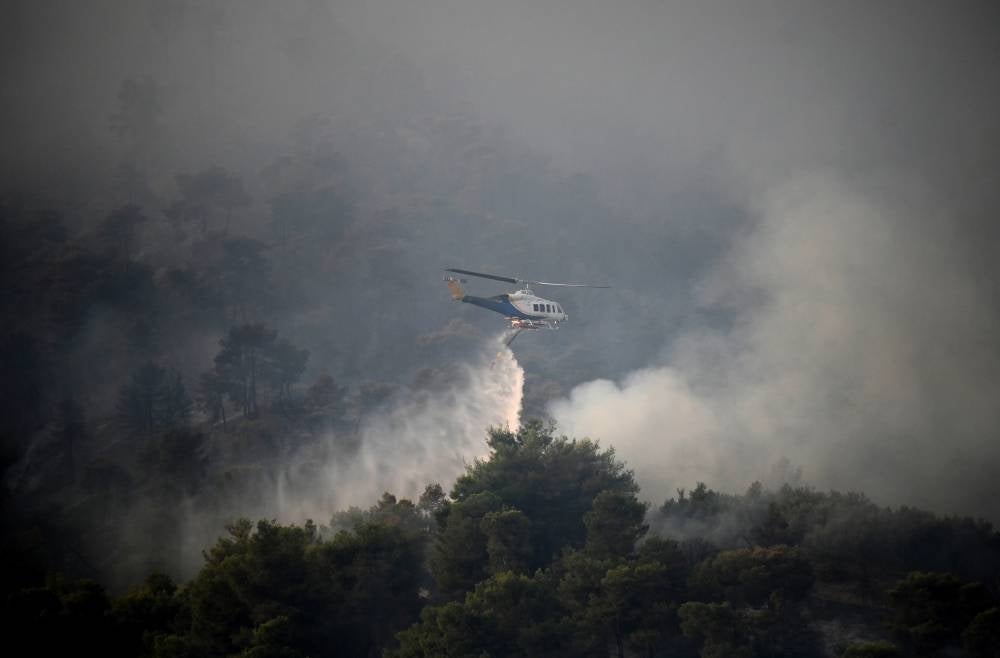 A firefighting helicopter drops water to extinguish a wildfire, in Diakopto, Egio, Greece, 24 July 2023. Firefighting forces along with volunteers in Rhodes, Corfu, Egio, Karystos and Yliki battled flames throughout the night, while airplanes started to operate early in the morning. Photo by EPA Images 