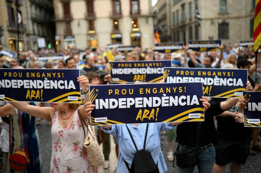 Demonstrators hold signs reading "Enough deception! Independence now !" as they take part in a protest called by the Catalan National Assembly (ANC) a day after Spain's general election, in Barcelona on July 24, 2023. The conservative Popular Party (PP) came first as predicted by the polls, but won far fewer mandates than expected -- taking 136 of the parliament's 350 seats. Even with the 33 seats won by the far-right Vox, its sole possible ally, the two parties will fall short of the 176 seats needed for a working majority. (Photo by Josep LAGO / AFP)