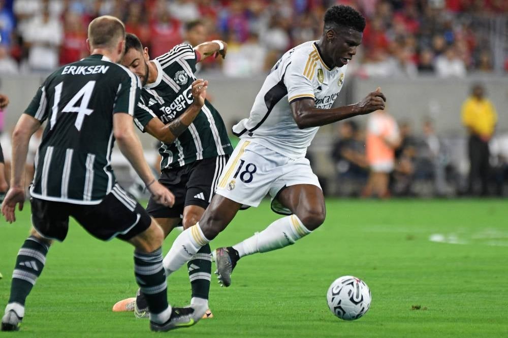 Manchester United's Danish midfielder Christian Eriksen (L) and Manchester United's Portuguese midfielder Bruno Fernandes (C) fight for the ball with Real Madrid's French midfielder Aurelien Tchouameni (R) during a pre-season friendly football match between Real Madrid CF and Manchester United FC at NRG Stadium in Houston, Texas, on July 26, 2023. - Photo by AFP