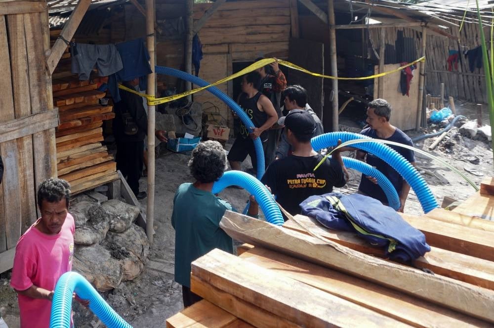 Rescue workers insert a hose to extract water from an illegal gold mining pit at Pancurendang village in Banyumas, on July 26. - Photo by Dida Nuswantara / AFP 