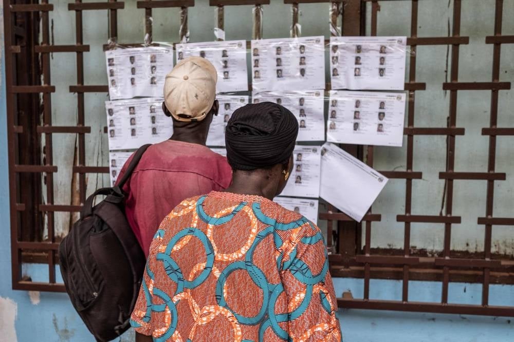 Voters check for their names on the voters roll at the Boganda high school in Bangui, on July 30, 2023. The Central African Republic began voting on Sunday in a referendum on a new constitution that would allow President Faustin-Archange Touadera to seek a third term in a country which has endured several coups. In 2020 Touadera won a second term through to 2025, after a vote interrupted by several incursions by armed rebel groups, while he also had to overcome allegations of fraud. (Photo by Barbara DEBOUT / AFP)