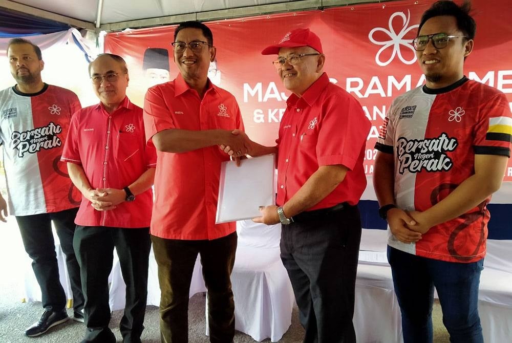Ahmad Faizal (center)receives the new member form from the Chairman of Sayap Bersekutu Bersatu Perak, Dr Richard Ng at the Majlis Ramah Mesra and Bersatu Perak new member intake at the Bersatu Perak office area yesterday.