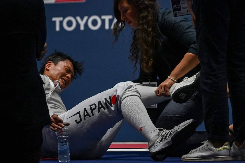 Japan's Kyosuke Matsuyama is treated for injury during the first semifinal of the Foil Men's Senior Individual event, against US Nick Itkin, as part of the FIE Fencing World Championships at the Fair Allianz MI.CO (Milano Convegni) in Milan, on July 27, 2023. (Photo by Andreas SOLARO / AFP)