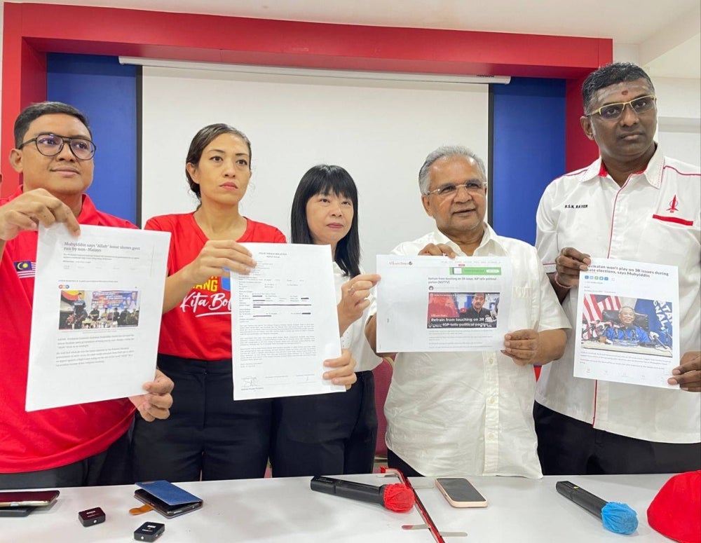 Syerleena (second from the left) dan Rayer (right) showing the copy of the police report lodged regarding Muhyiddin's claims on the Allah wording issue.