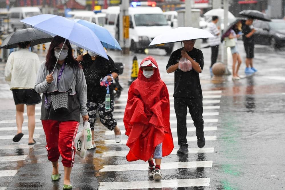 People walk amid the rain in Beijing, capital of China. Impacted by Typhoon Doksuri, the fifth typhoon of this year, heavy rainfall has hit north China regions, including Beijing, Hebei and Shandong. (photo by Xinhua/Ju Huanzong)