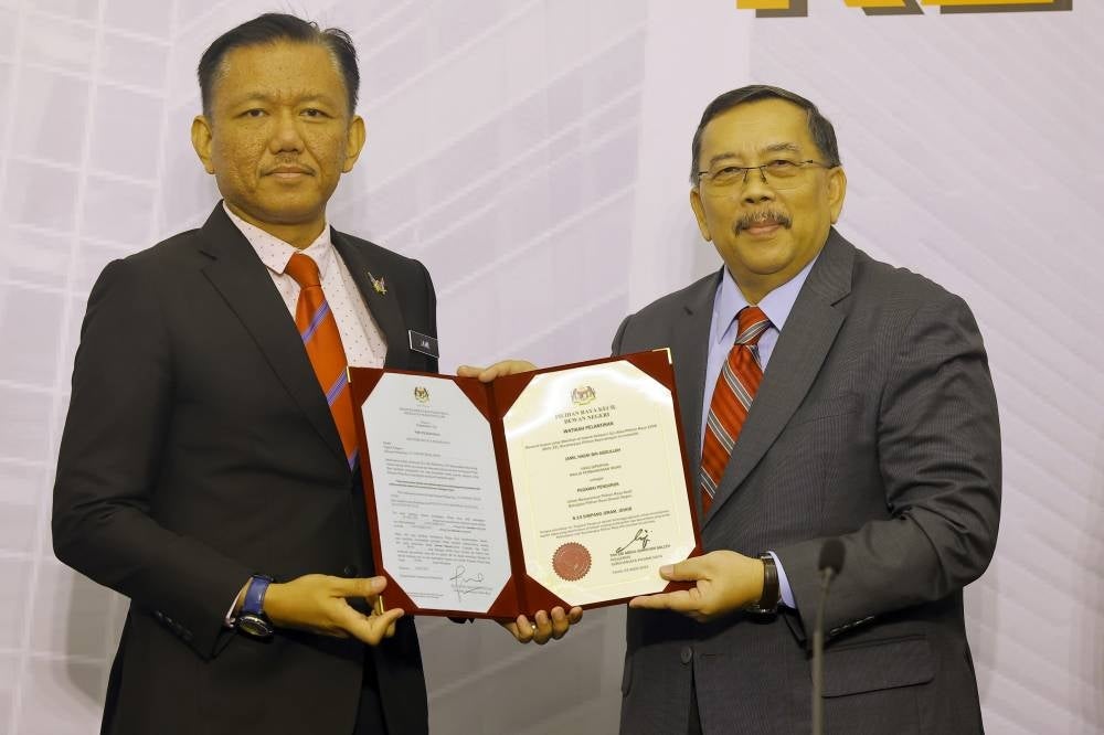 EC chairman Tan Sri Abdul Ghani Salleh (right) handing over an appointment letter to Head of Muar Municipal Council Jamil Hasni Abdullah as the returning officer for the Simpang Jeram by-election at the EC office, today. - Photo by Bernama
