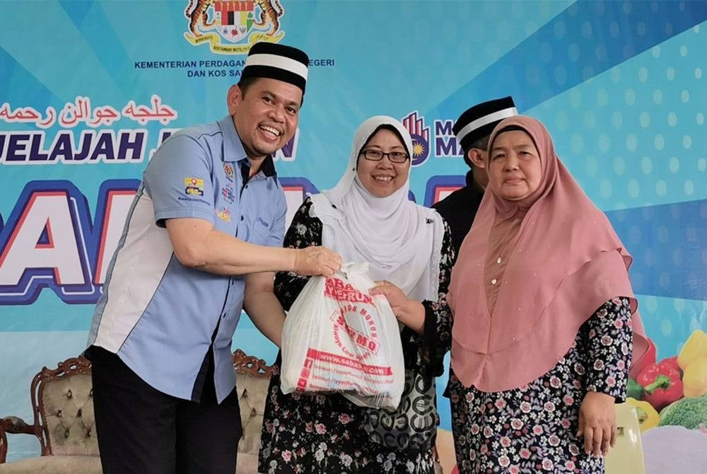 Domestic Trade and Cost of Living Deputy Minister Fuziah Salleh (centre) with the ministry's state director Saharuddin Mohd Kia (left) handing out daily necessities for recipients in Jelajah Rahmah Sales programme on Saturday.