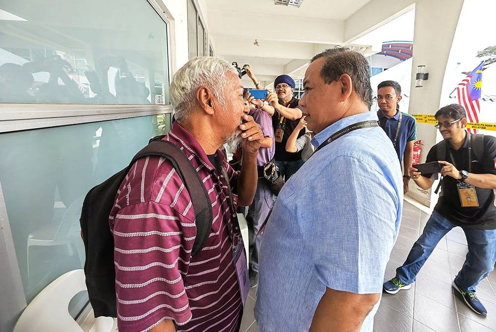 Aminuddin (kanan) berbisik kepada calon bebas Bujang Abu yang turut meninjau pusat pengundian awal di Balai Polis Sikamat