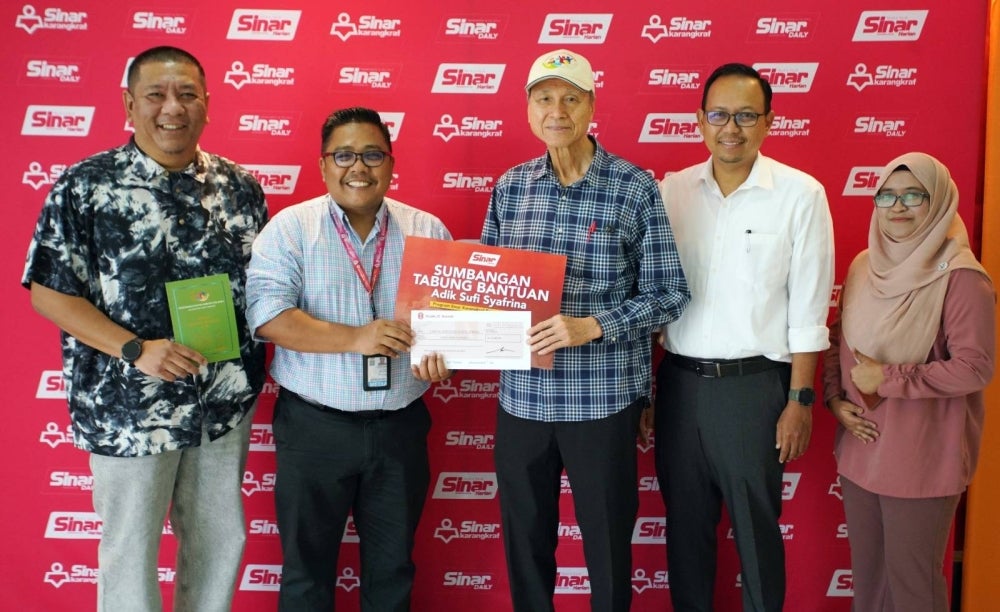 Lee (middle) hands over the donation check to the Sinar Harian Chief Editor Zamri Rambli at the Karangkraf Complex today