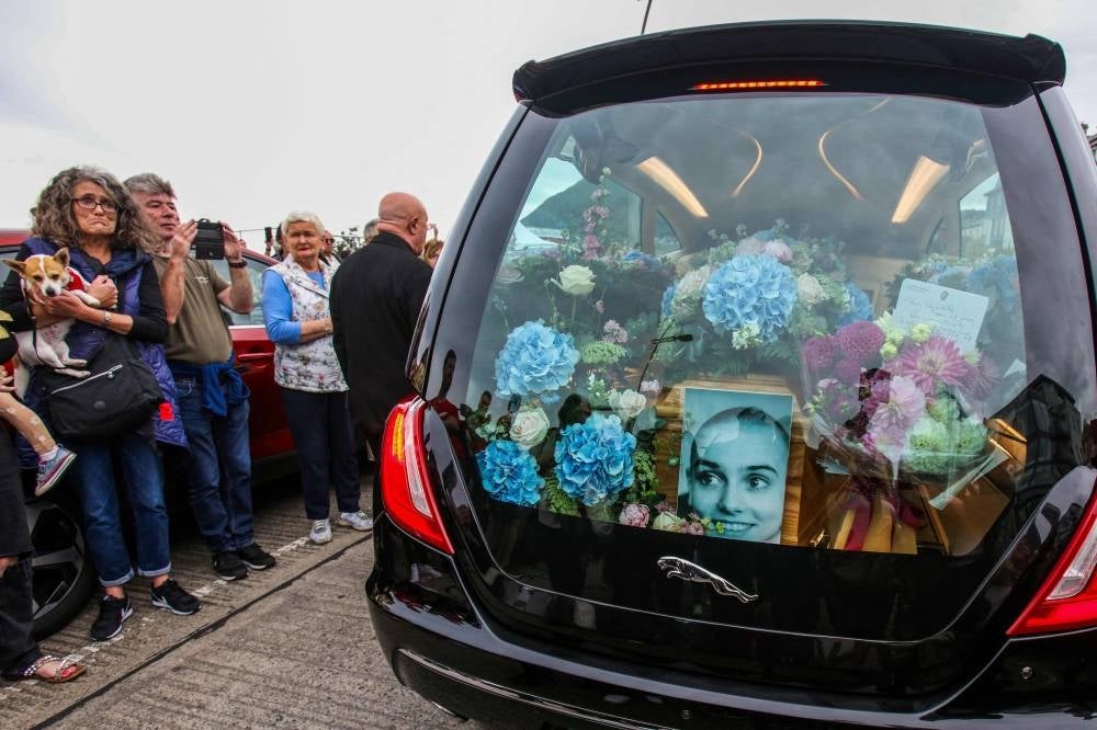 A photograph taken on August 8, 2023 shows the coffin and a picture of late Irish singer Sinead O'Connor, in the hearse during her funeral procession outside her former home in Bray, eastern Ireland - AFP 