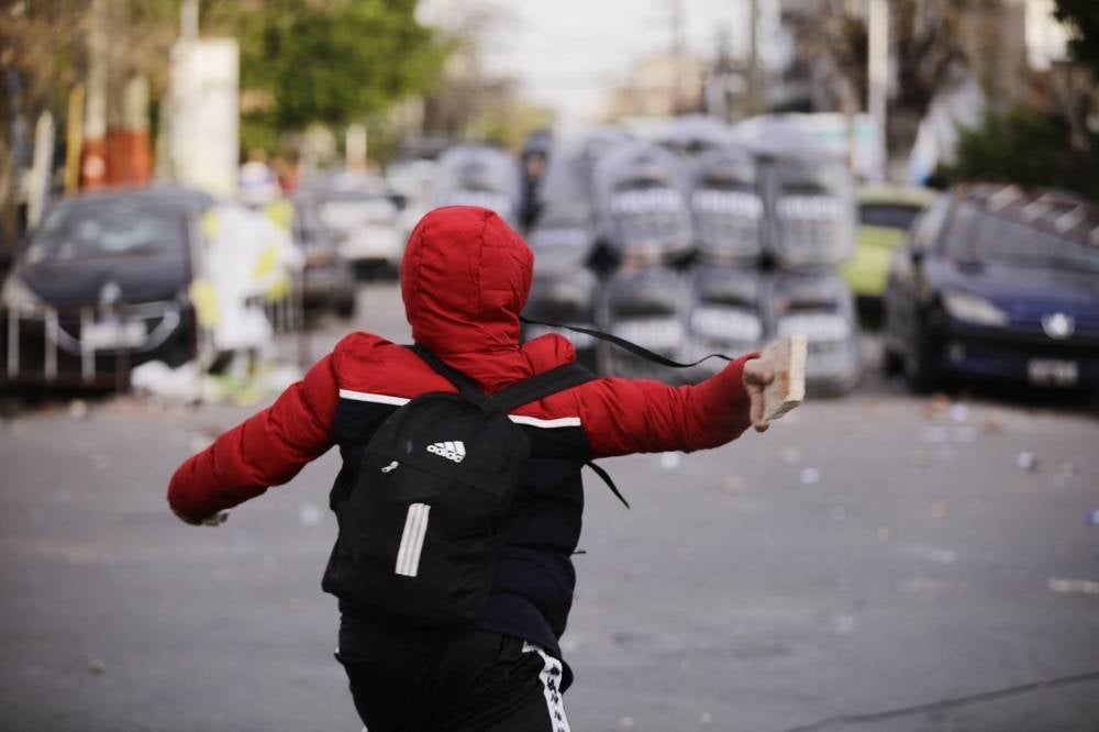 A protester clashes with police during a demonstration held by residents of the Lanus municipality demanding justice for the death of an 11-year-old Argentine girl on Wednesday after she robbed of her backpack and beaten on the way to school. - (Photo by Emiliano Lasalvia / AFP)