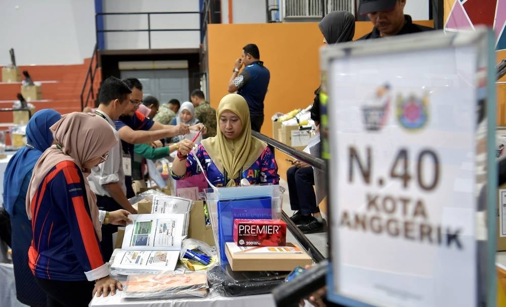 Election Commission personnel checking the voting equipment for early voting at the Selangor Police headquarters at Dewan Besar Tanjung Majlis Bandaraya Shah Alam on Aug 8. (Photo by BERNAMA) 