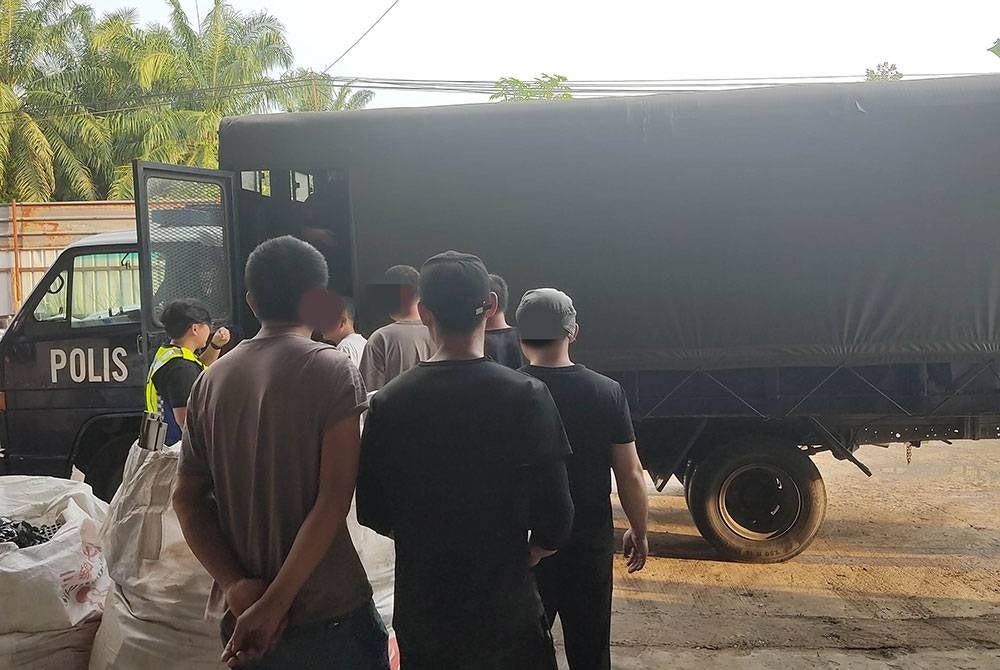 Police arresting foreign workers at an illegal scarp metal factory.
