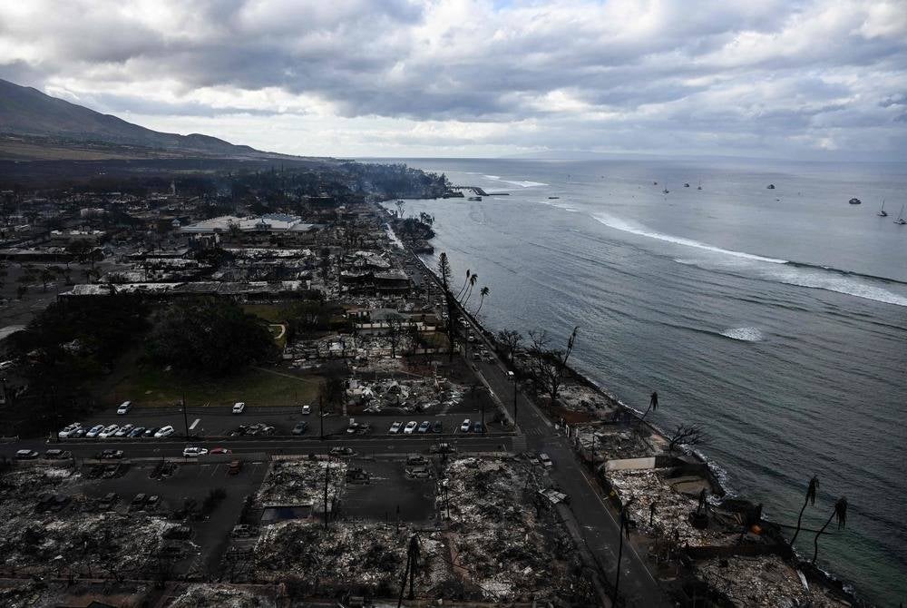 An aerial image taken on Aug 10, 2023 shows destroyed homes and buildings burned to the ground in Lahaina along the Pacific Ocean in the aftermath of wildfires in western Maui, Hawaii. (Photo by Patrick T. Fallon / AFP)