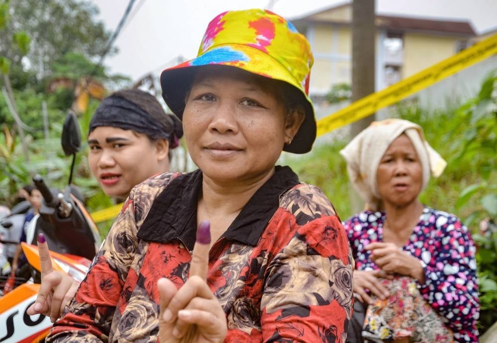 The Orang Asli women showing off their inked fingers after casting their votes at polling centre Sekolah Kebangsaan Kuala Betis here today. Photo by Bernama.