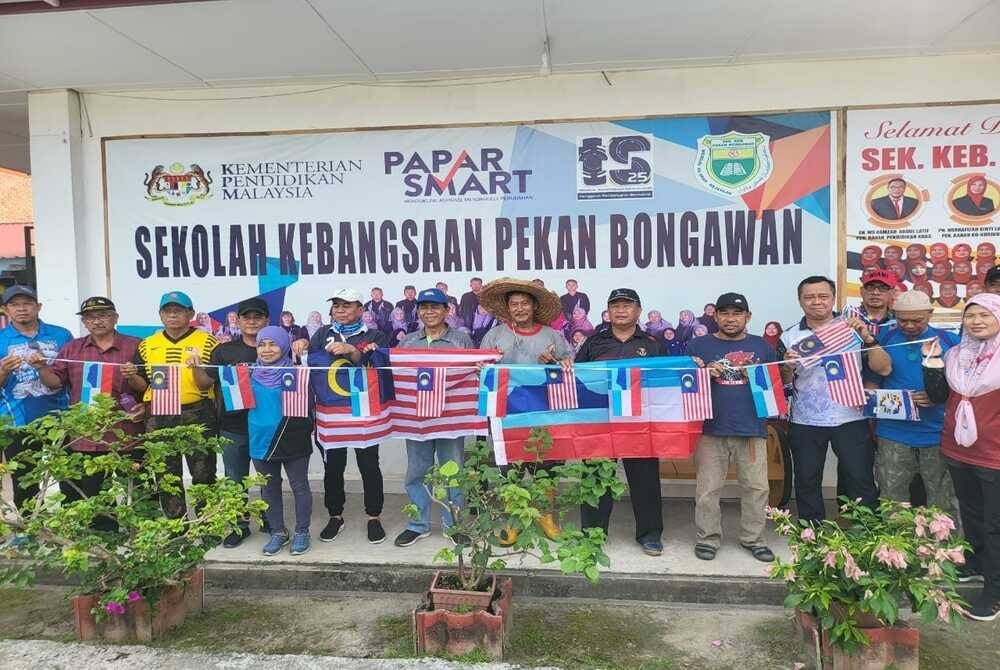 Dr Daud waving the Jalur Gemilang flag at the 'gotong royong' event at SK Pekan Bongawan Kimanis, Papar.