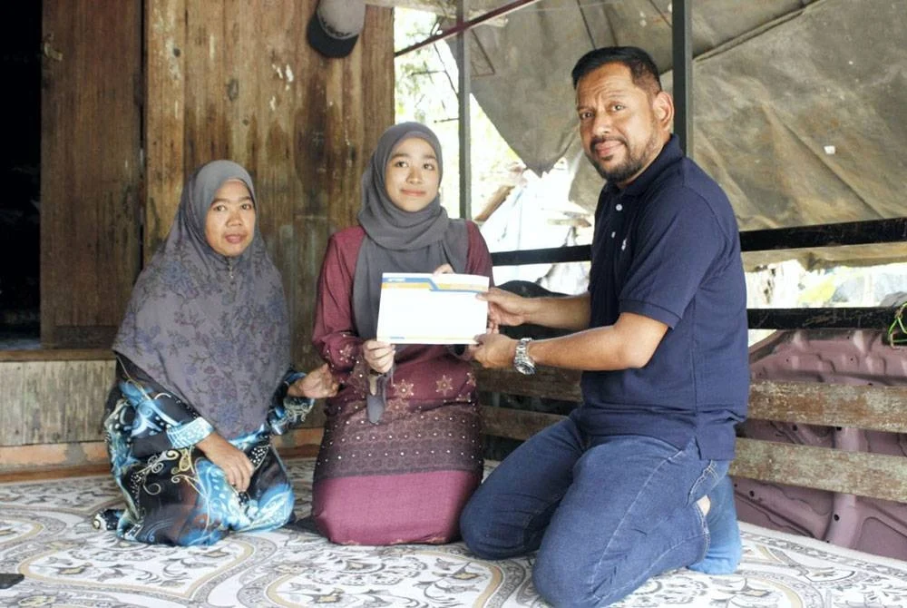 Syaiful Rizal presents a cash donation to Fatin Nur Aqilah at the student's residence on Monday. – Photo by SINAR
