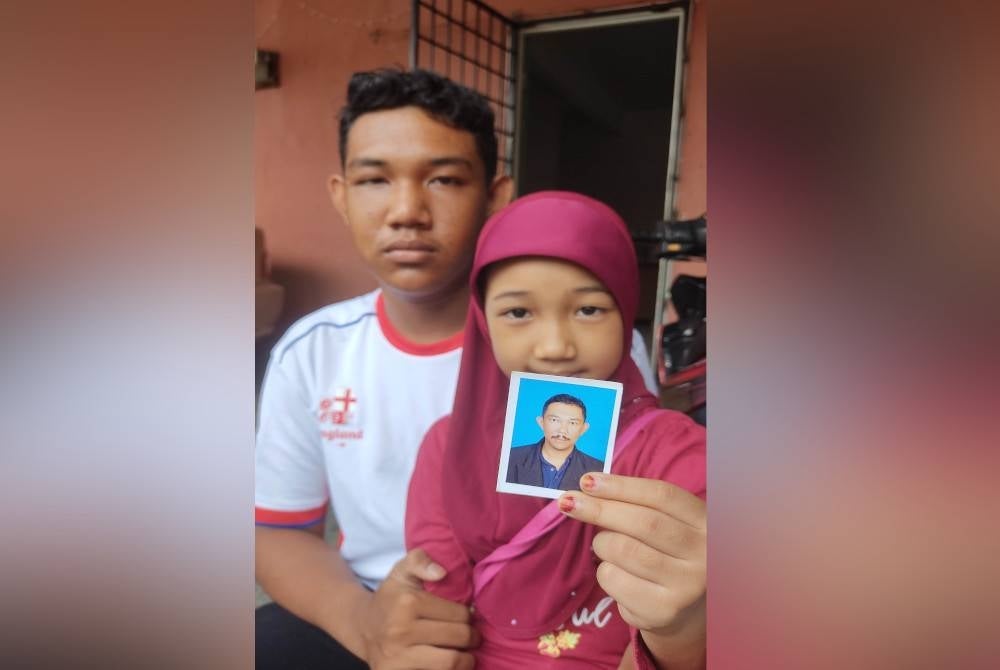 Sharul and Nur Izzara showing the picture of their father to be kept safe while they were on their way to a mall in Sepang - FILE PIX