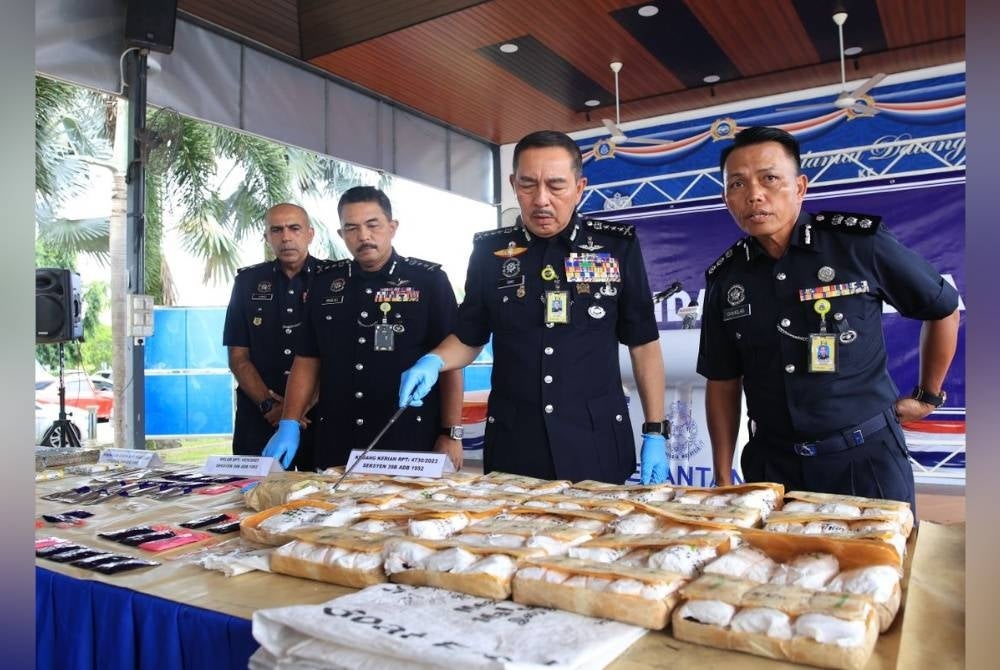Muhamad Zaki (second from the right) displays the seized yaba pills in Kampung Kubang Kacang, Kota Bharu.
