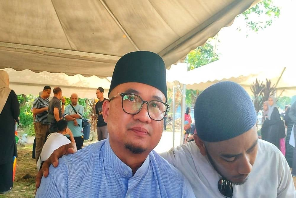 Fadzli (left) shares the sadness of losing his best friend while being comforted by the late's younger brother, Nurul Qomar on Sunday.