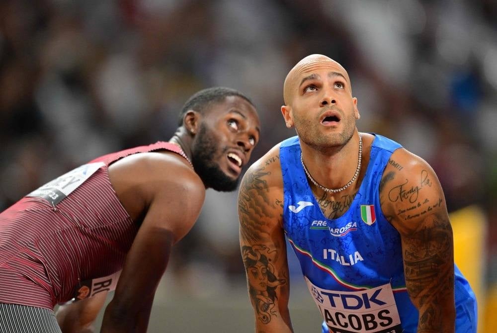 Italy's Lamont Marcell Jacobs (R) and Canada's Brendon Rodney (L) look up at the big screen having competed in the men's 100m heats during the World Athletics Championships at the National Athletics Centre in Budapest on Aug 19, 2023. (Photo by ANDREJ ISAKOVIC / AFP)