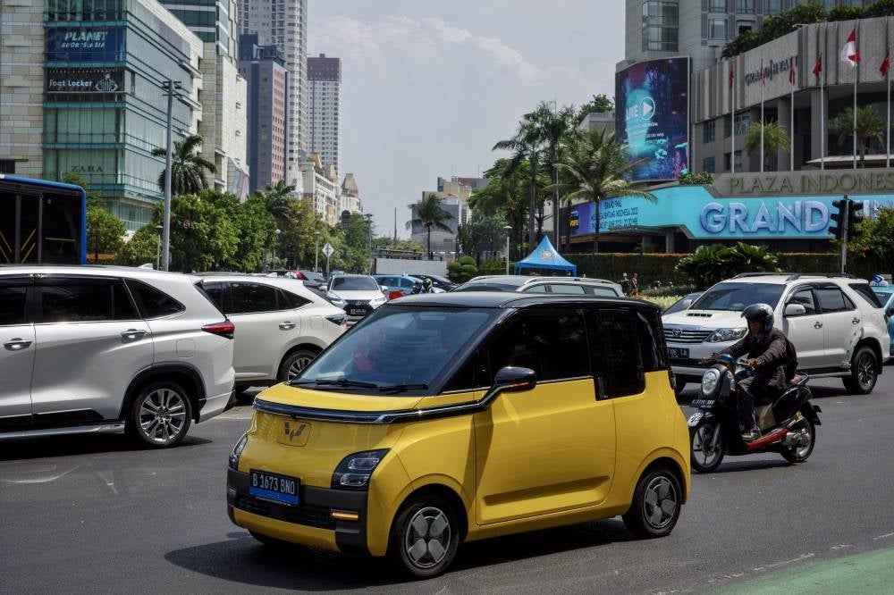 An electric car drives on a main road in Jakarta on June 7, 2023. - (Photo by BAY ISMOYO / AFP)