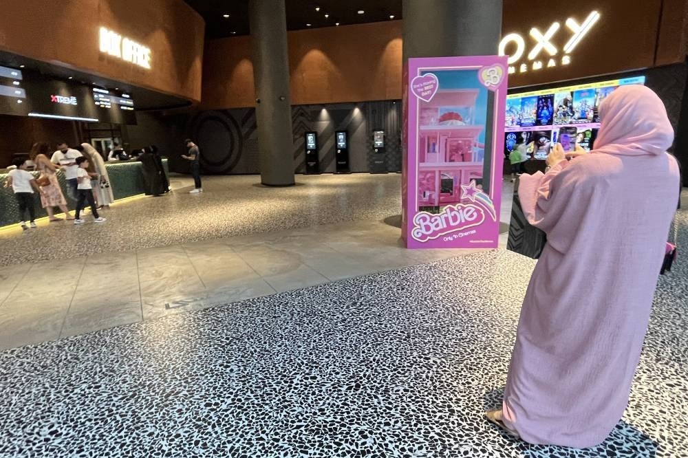 A woman in pink stands at the entrance of a movie theatre screening the film "Barbie", in Dubai on August 14, 2023. Photo by Giuseppe Cacae/AFP