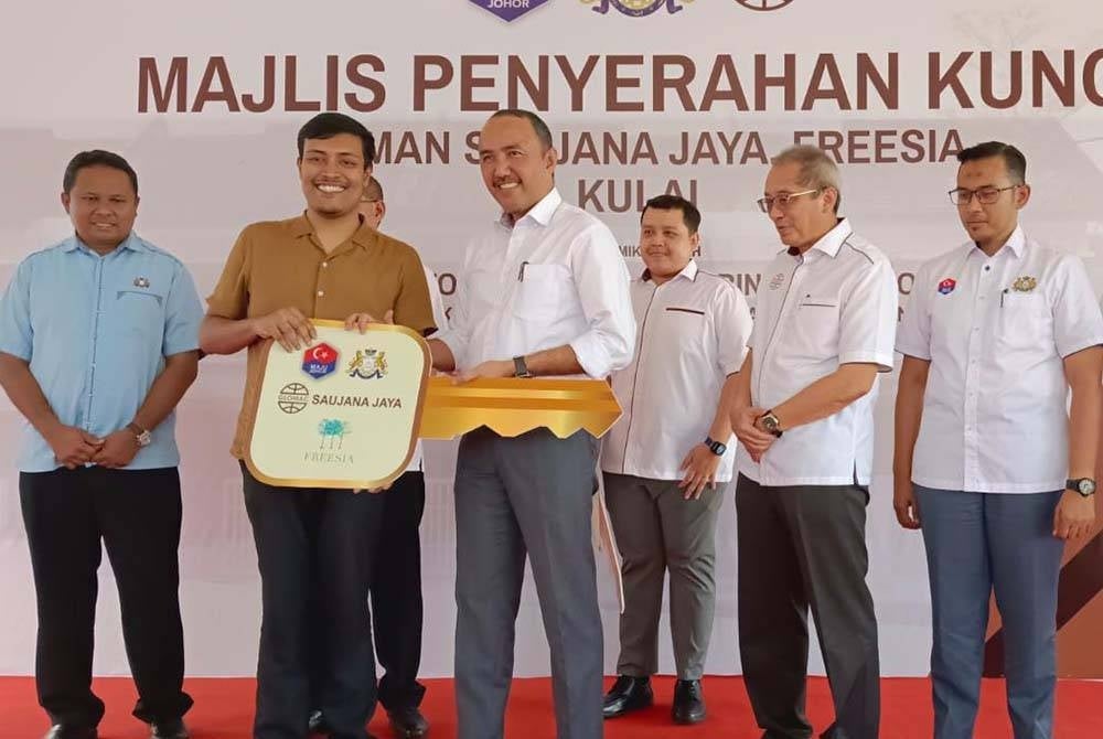Jafni handing over the key to a recepient at the Taman Saujana Jaya Key Handover Ceremony, Kulai earlier today.