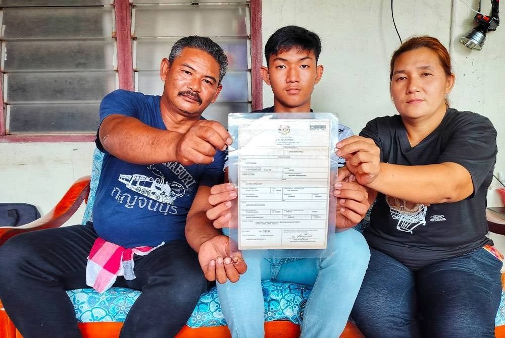 Khathanak (center) with his mother and father showing his birth certificate with the word 'non-citizen' written on it at their home here on Tuesday.