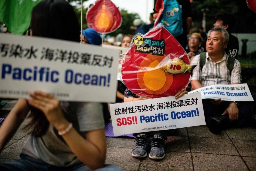 An activist holds a placard that reads "SOS!! Pacific Ocean!" during a protest against the planned release of wastewater from Japan's stricken Fukushima nuclear plant into the Pacific. Photo by Anthony Wallace/AFP