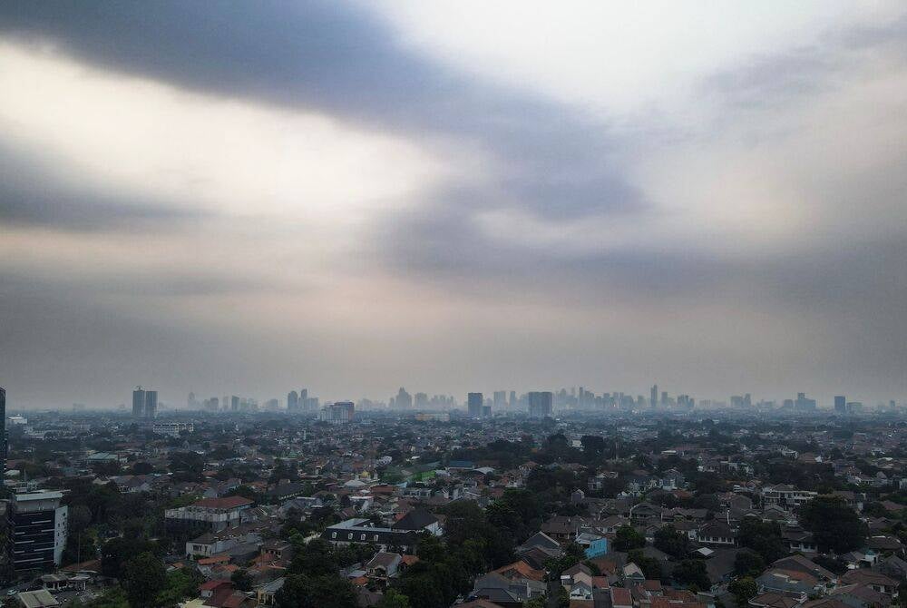 An aerial view taken on August 20, 2023 shows buildings and houses under hazy skies in Jakarta. (Photo by BAY ISMOYO / AFP)