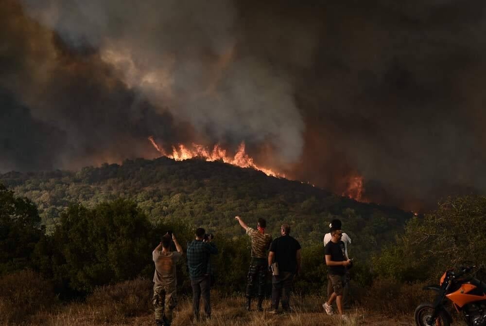People look at the wildfire raging in a forest in Sikorahi, near Alexandroupoli, northern Greece, on Aug 23, 2023. (Photo by Sakis MITROLIDIS / AFP)