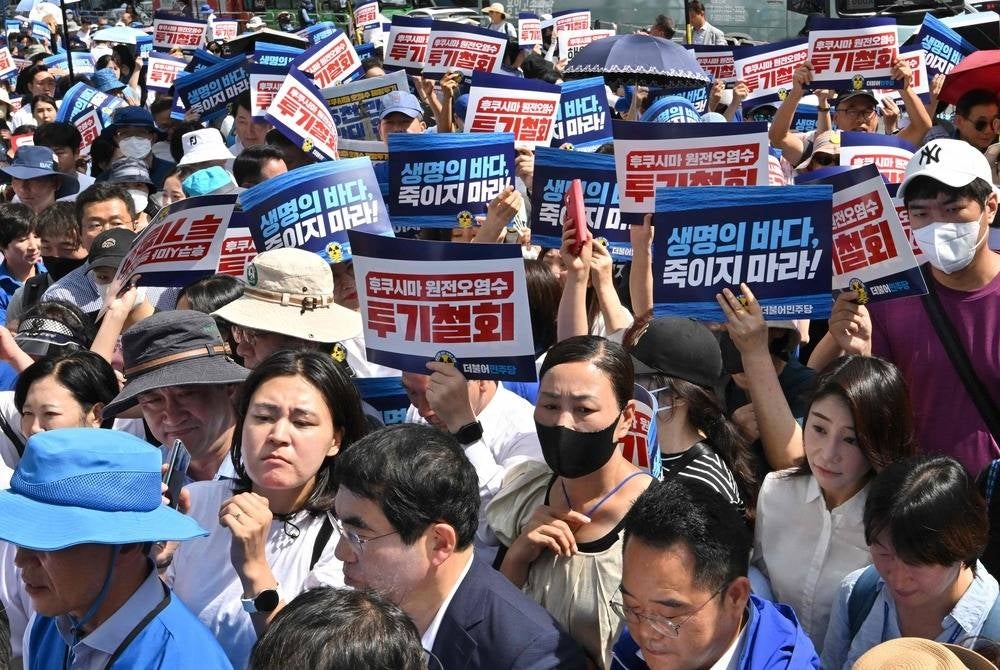 South Korea's main opposition Democratic Party members hold placards reading "Stop dumping Fukushima nuclear contaminated water into the ocean!" during a rally against Japan's discharge of treated wastewater from the crippled Fukushima nuclear power plant, at Gwanghwamun Square in Seoul on Aug 25, 2023. (Photo by Jung Yeon-je / AFP)