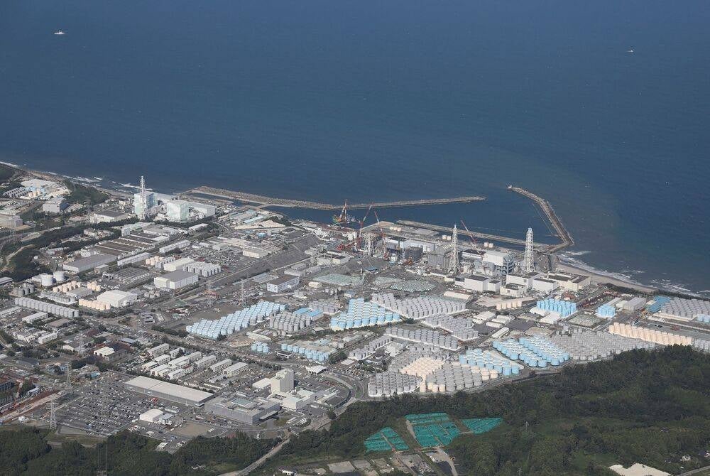 TOPSHOT - This aerial picture shows storage tanks (bottom) used for storing treated water at Tepco's crippled Fukushima Daiichi Nuclear Power Plant in Okuma, Fukushima prefecture on Aug 24, 2023. (Photo by JIJI PRESS / AFP) 