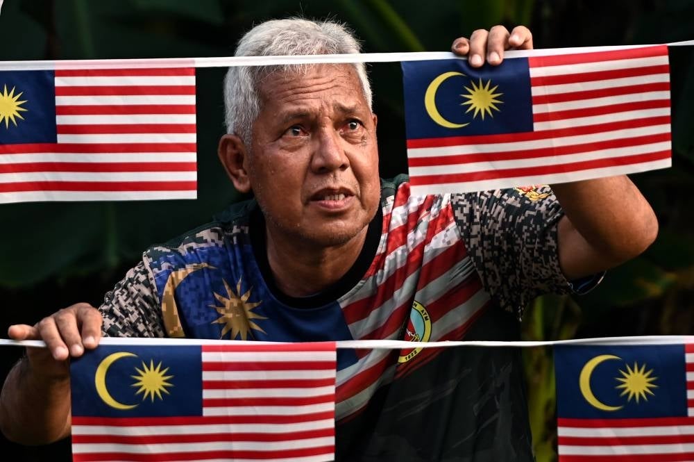 Retired army Sidek Hussin, 63, or better known as Pok Zam put up the Jalur Gemilang in front of his house ahead of the 66th National Day on August 31. (BERNAMA PHOTO)