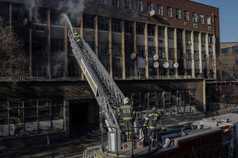 Firefighters extinguish a fire in a building in Johannesburg. Photo by Michele Spatari/AFP