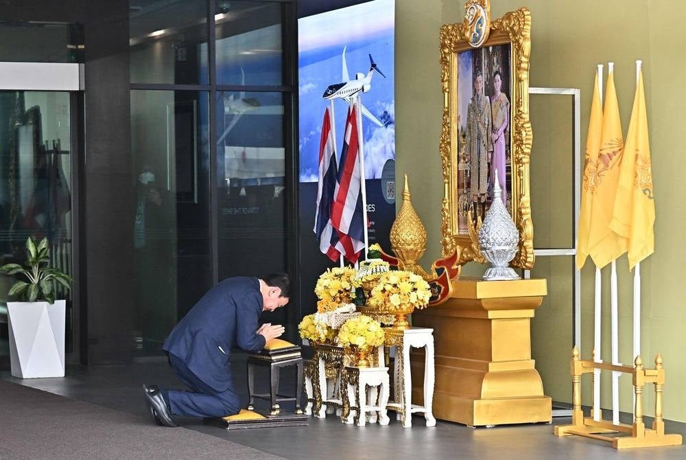 (FILES) Former Thai Prime Minister Thaksin Shinawatra bows in homage to the king's portrait after landing at Bangkok's Don Mueang airport on Aug 22. (Photo by Lillian SUWANRUMPHA / AFP)